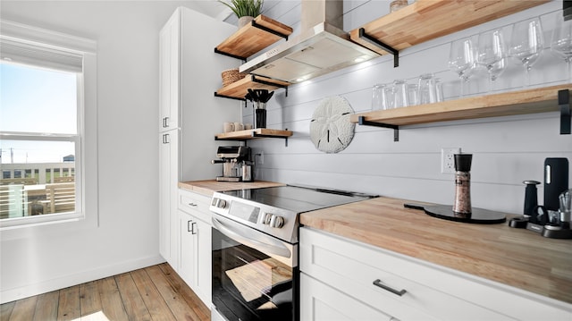 kitchen with stainless steel electric range oven, range hood, and white cabinetry