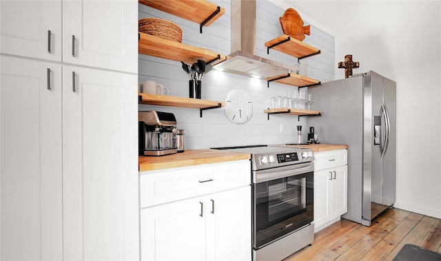 kitchen with appliances with stainless steel finishes, wooden counters, white cabinetry, island range hood, and light hardwood / wood-style flooring