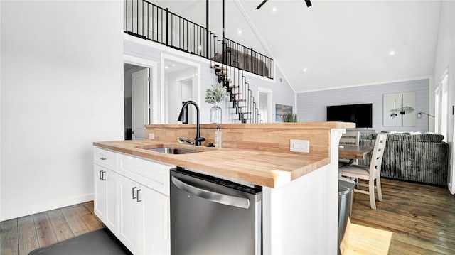 kitchen with wood counters, hardwood / wood-style floors, dishwasher, a center island with sink, and sink