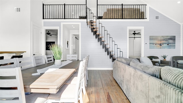 living room featuring ceiling fan, light wood-type flooring, and a high ceiling