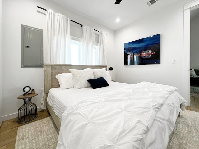 bedroom featuring electric panel, visible vents, baseboards, a ceiling fan, and light wood-style flooring