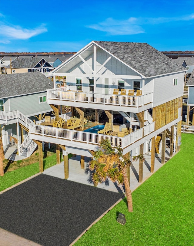 back of house featuring roof with shingles, a lawn, a deck, a residential view, and stairs