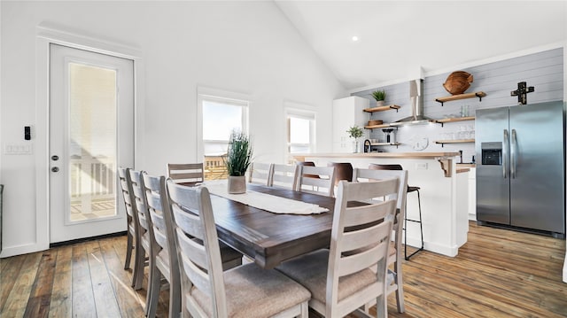 dining room with light hardwood / wood-style flooring, sink, and high vaulted ceiling