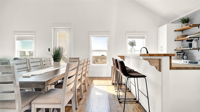 dining space featuring high vaulted ceiling and light hardwood / wood-style floors