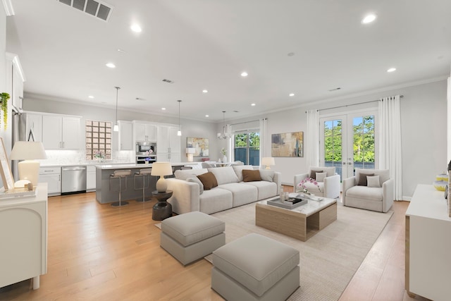 living room with french doors, sink, ornamental molding, and light hardwood / wood-style floors