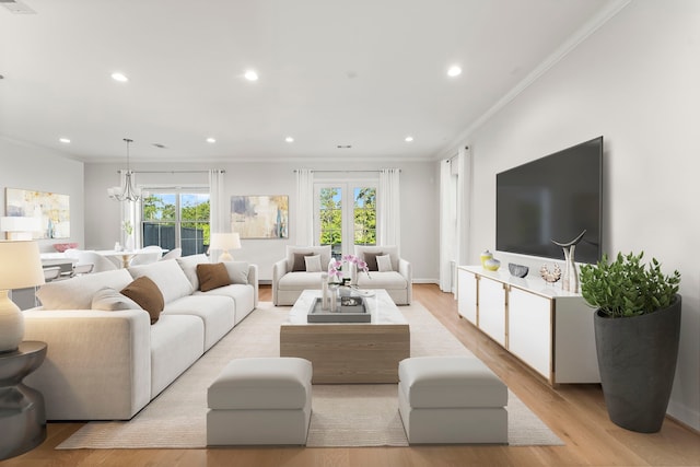 living room featuring french doors, an inviting chandelier, light hardwood / wood-style floors, and crown molding