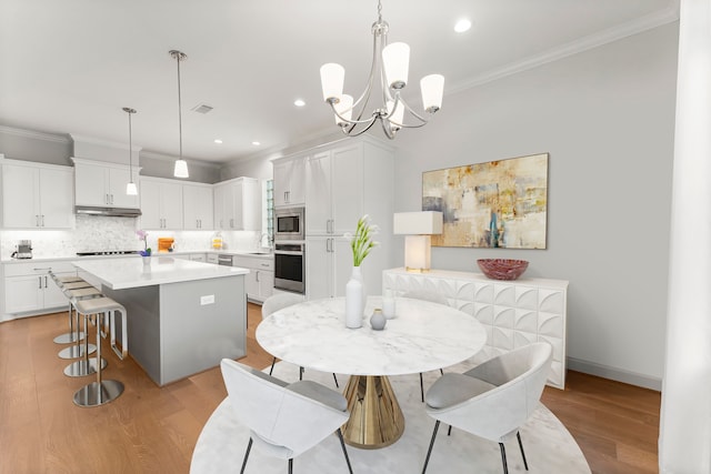 dining room featuring light hardwood / wood-style flooring, crown molding, and a chandelier