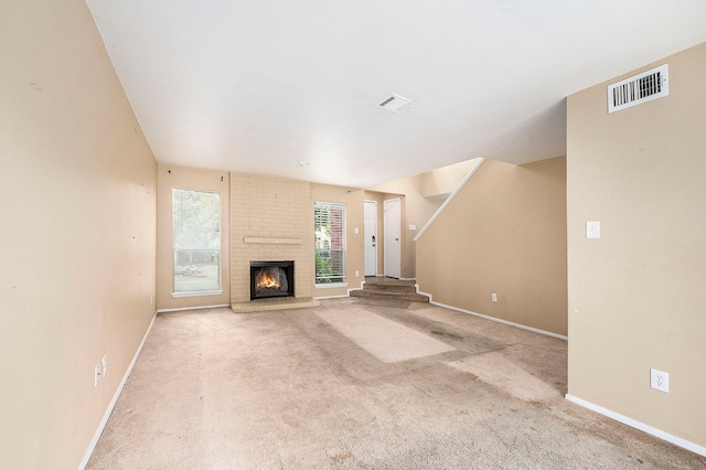 unfurnished living room featuring brick wall, light colored carpet, and a brick fireplace