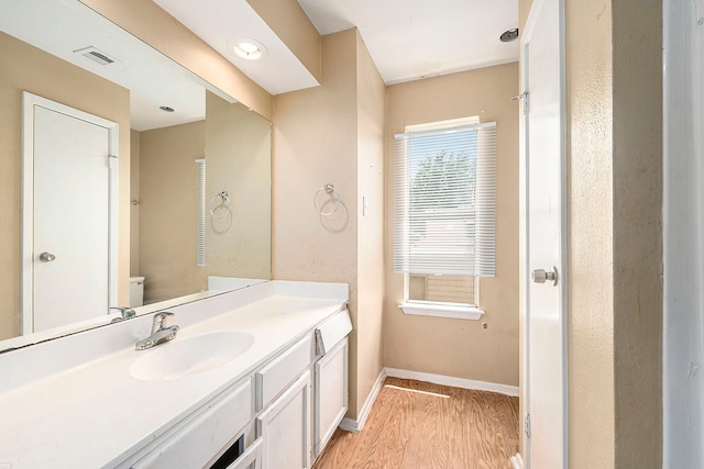 bathroom featuring wood-type flooring, vanity, and toilet