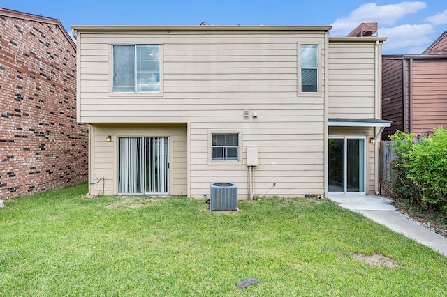 rear view of property featuring a lawn and central air condition unit