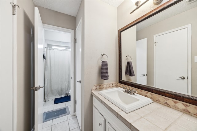 bathroom with a textured ceiling, tile patterned floors, and vanity