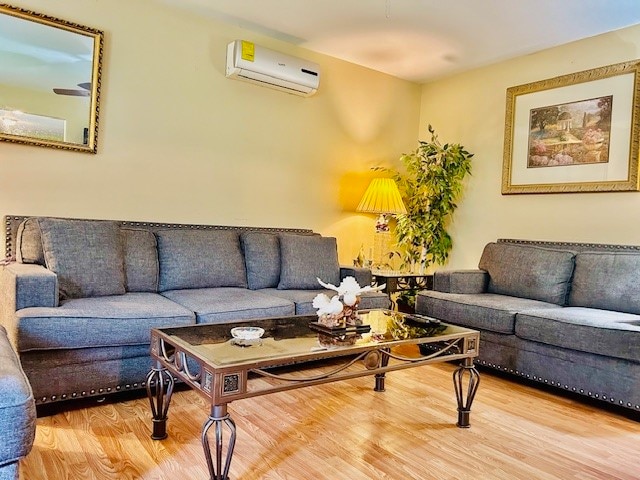 living room featuring light wood-type flooring and an AC wall unit