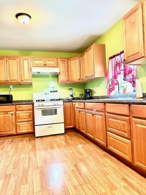 30470 Reids Prairie Rd, Waller, TX 77484 - kitchen with white range with gas cooktop, a sink, light wood-style floors, under cabinet range hood, and black microwave