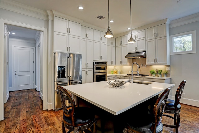 kitchen featuring appliances with stainless steel finishes, dark hardwood / wood-style floors, a kitchen island with sink, and white cabinetry