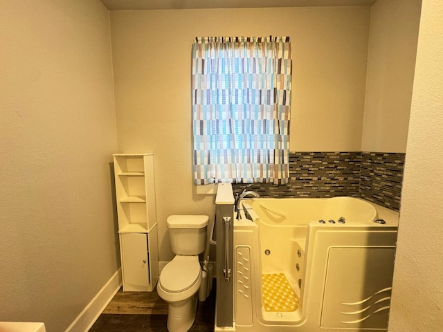 bathroom with decorative backsplash, toilet, a bathtub, and hardwood / wood-style floors