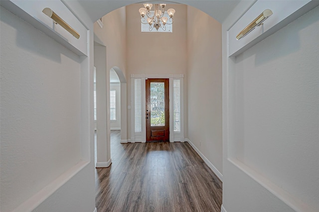 entrance foyer with dark hardwood / wood-style flooring, a towering ceiling, and a notable chandelier