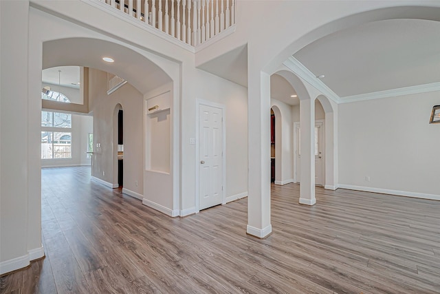 interior space featuring crown molding, light wood-type flooring, and a high ceiling