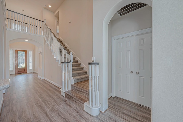 entryway with light hardwood / wood-style flooring and a towering ceiling