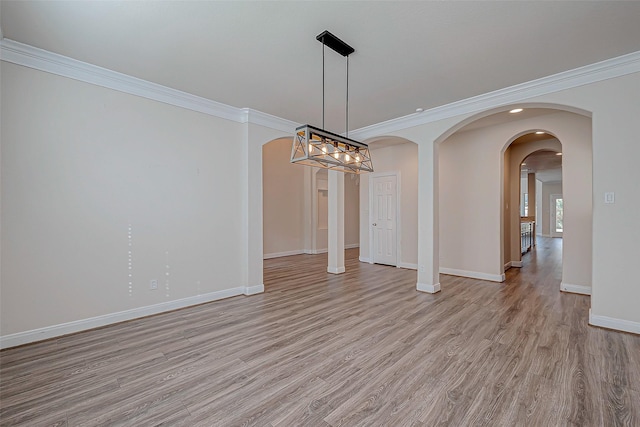 unfurnished dining area with baseboards, light wood-style floors, arched walkways, and ornamental molding