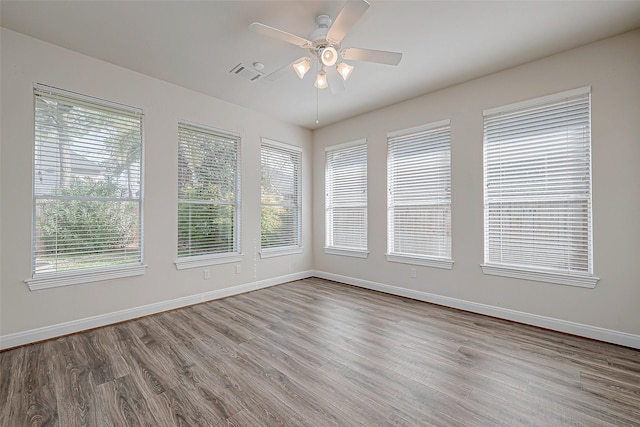 spare room with ceiling fan, wood finished floors, visible vents, and baseboards