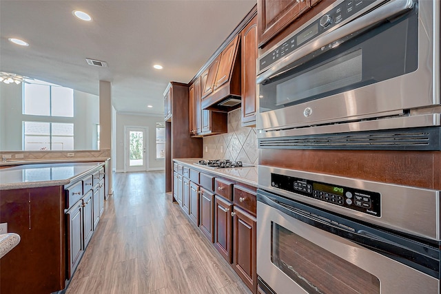 kitchen with tasteful backsplash, appliances with stainless steel finishes, and light hardwood / wood-style floors