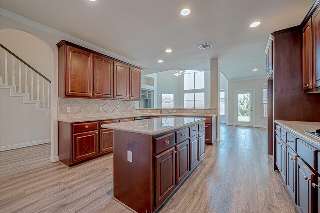 kitchen with light hardwood / wood-style floors, backsplash, crown molding, and a kitchen island