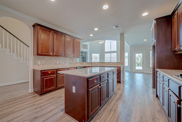 kitchen with light wood-style flooring, visible vents, backsplash, and a center island