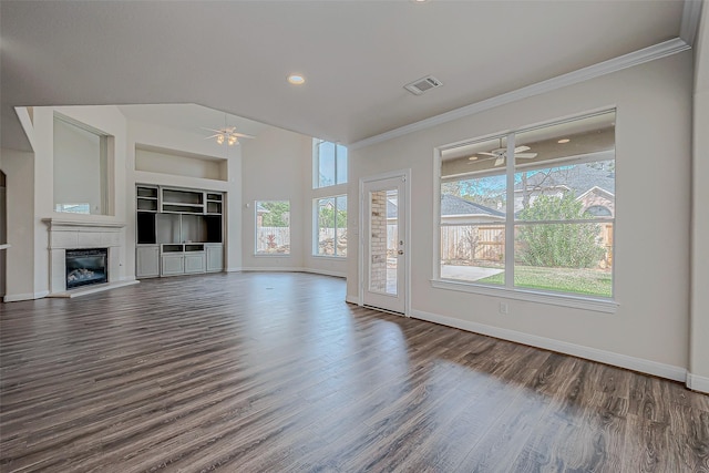 unfurnished living room featuring dark wood-type flooring, a tile fireplace, built in features, and ornamental molding