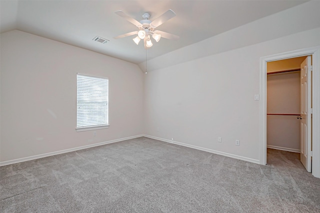 unfurnished bedroom with a spacious closet, visible vents, lofted ceiling, and carpet floors