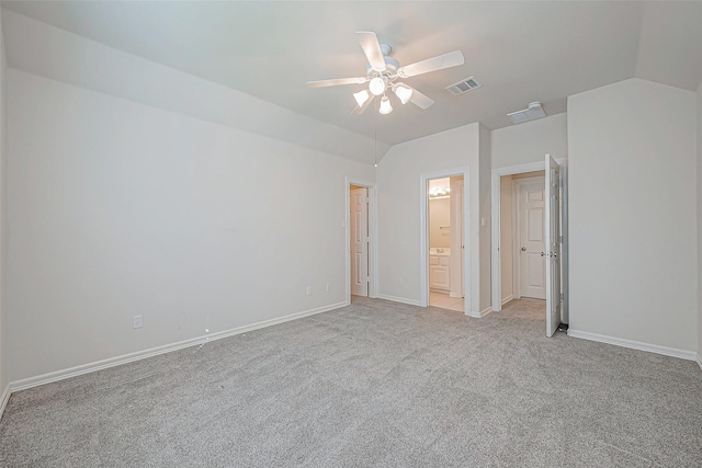 unfurnished bedroom featuring baseboards, visible vents, ensuite bath, lofted ceiling, and light carpet