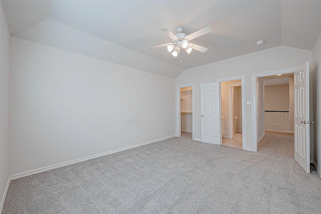 unfurnished bedroom with a spacious closet, ceiling fan, lofted ceiling, and light colored carpet