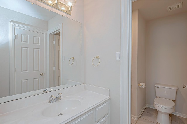 bathroom with toilet, vanity, and tile patterned flooring