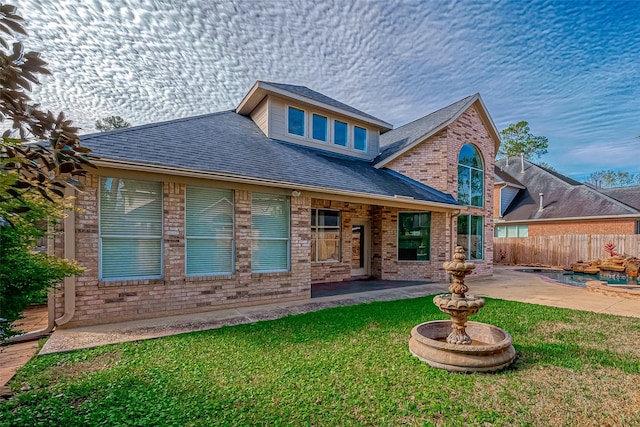 back of house featuring brick siding, a patio area, fence, and a lawn