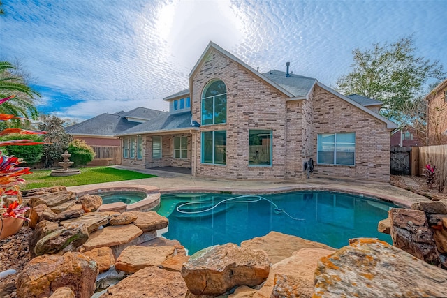 back of property with a patio area and a swimming pool with hot tub