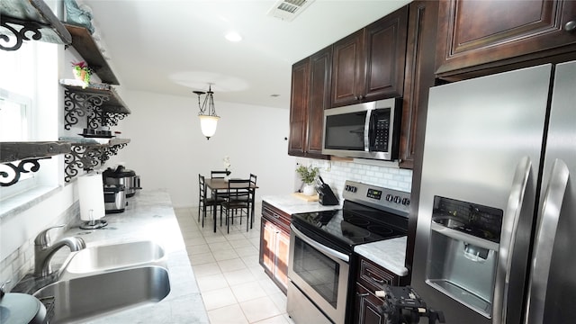 kitchen with hanging light fixtures, decorative backsplash, appliances with stainless steel finishes, sink, and dark brown cabinetry