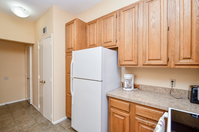 kitchen with white fridge, stove, and light tile patterned floors