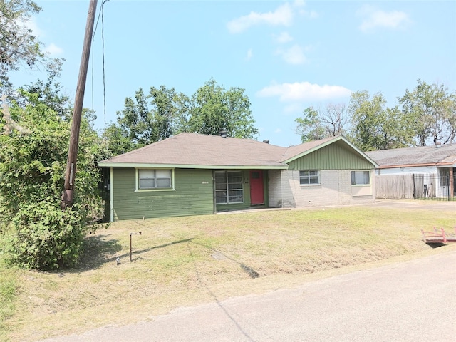 ranch-style house featuring a front yard, fence, and brick siding