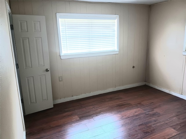 spare room featuring baseboards and dark wood-type flooring