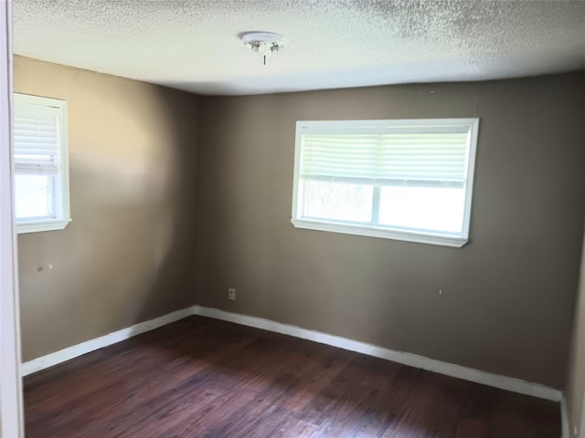 empty room with dark wood-style flooring, a healthy amount of sunlight, and baseboards