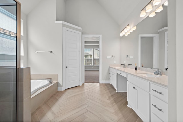 bathroom featuring a relaxing tiled tub, vanity, vaulted ceiling, and parquet floors