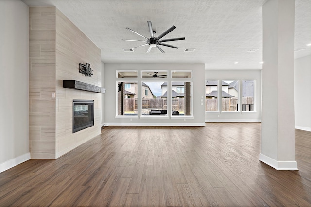 unfurnished living room with a healthy amount of sunlight, dark hardwood / wood-style floors, ceiling fan, and a fireplace