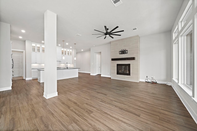 unfurnished living room with dark wood-type flooring, ceiling fan, plenty of natural light, and a fireplace