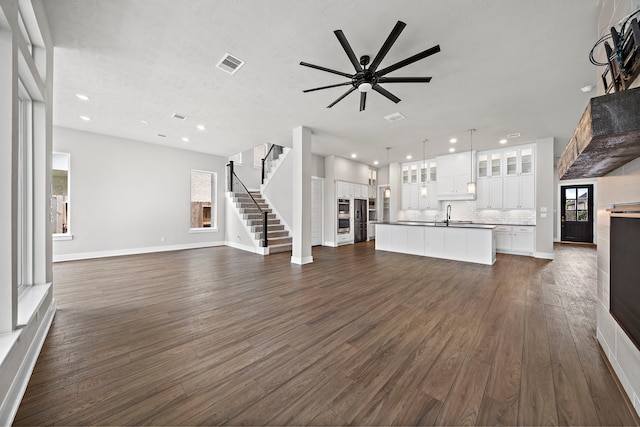 unfurnished living room with ceiling fan, dark hardwood / wood-style flooring, and sink