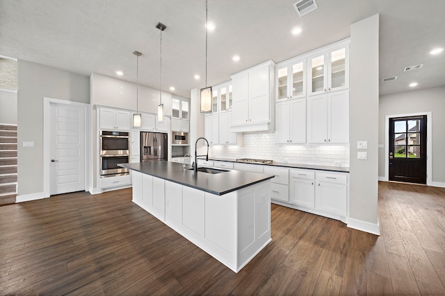 kitchen featuring pendant lighting, appliances with stainless steel finishes, an island with sink, and white cabinets