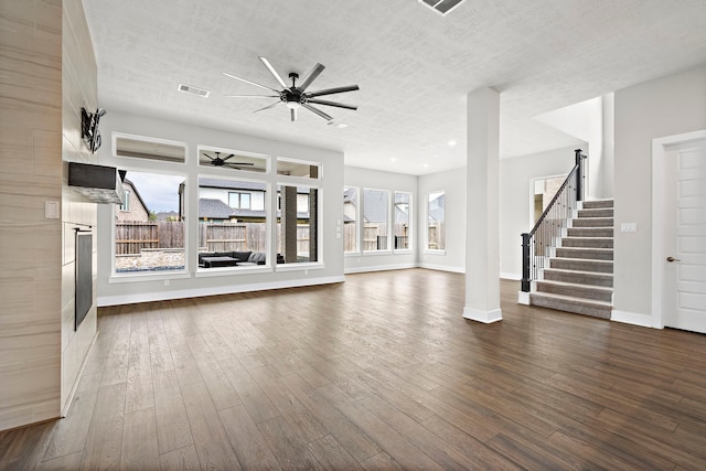 unfurnished living room featuring dark wood-type flooring, ceiling fan, and a textured ceiling