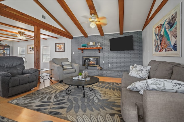 living room featuring a brick fireplace, ceiling fan, lofted ceiling with beams, hardwood / wood-style floors, and brick wall