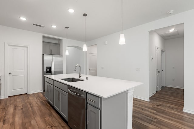 kitchen featuring stainless steel appliances, sink, dark hardwood / wood-style floors, an island with sink, and pendant lighting