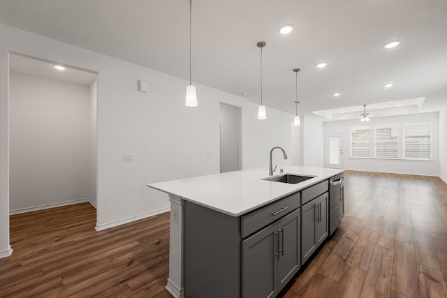 kitchen featuring dark hardwood / wood-style flooring, an island with sink, sink, and hanging light fixtures