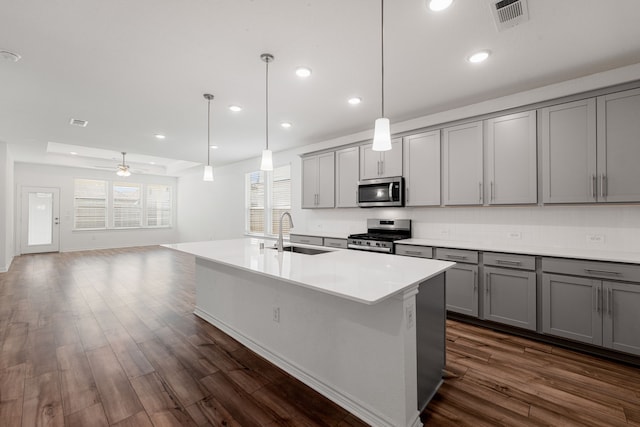 kitchen with gray cabinetry, dark hardwood / wood-style floors, stainless steel appliances, sink, and ceiling fan