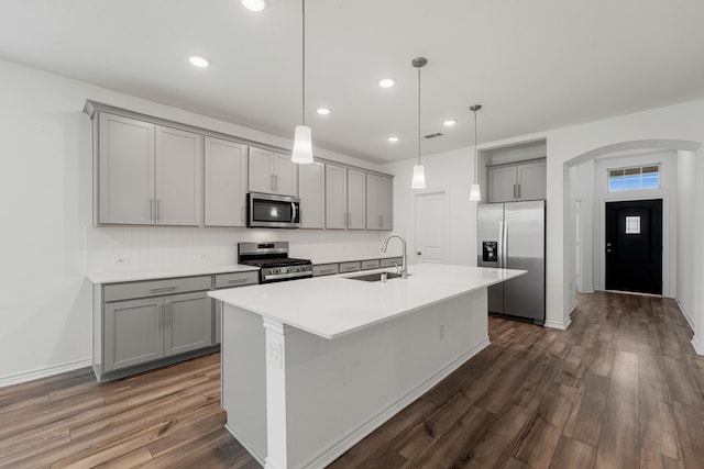 kitchen with dark wood-type flooring, decorative light fixtures, stainless steel appliances, and sink